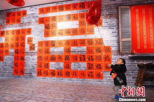 孩子在“福”字墻前玩耍著。 殷立勤 攝