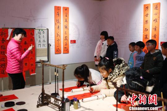 孩子在老師的指點下書寫春聯(lián)。 殷立勤 攝